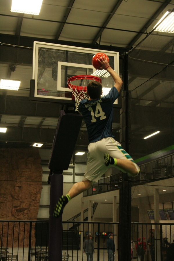 Boy in Air about to Slam Dunk on Trampoline Basketball Court